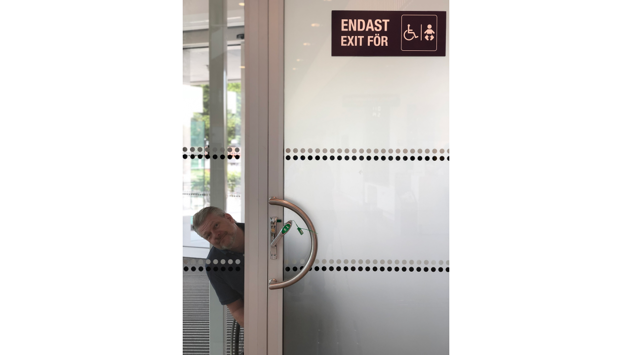 I am outside, looking through a glass door. A sign says "Only exit for", plus a wheelchair and a baby sign. I wonder where the baby's parents go.